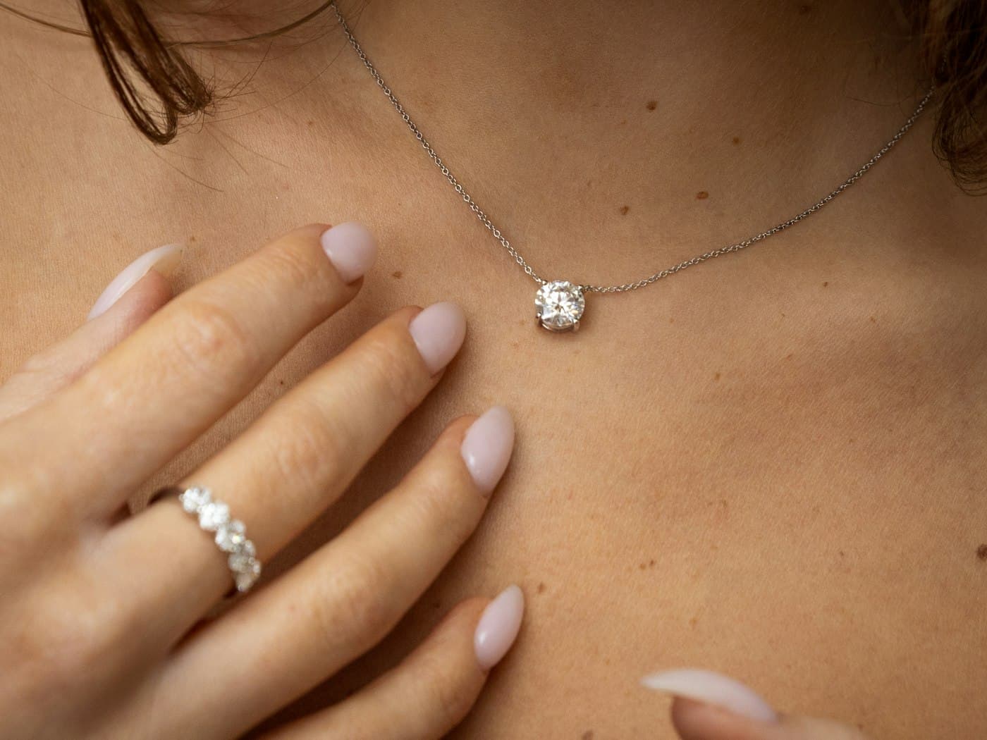 Close-up of a woman wearing a fine diamond necklace and rings